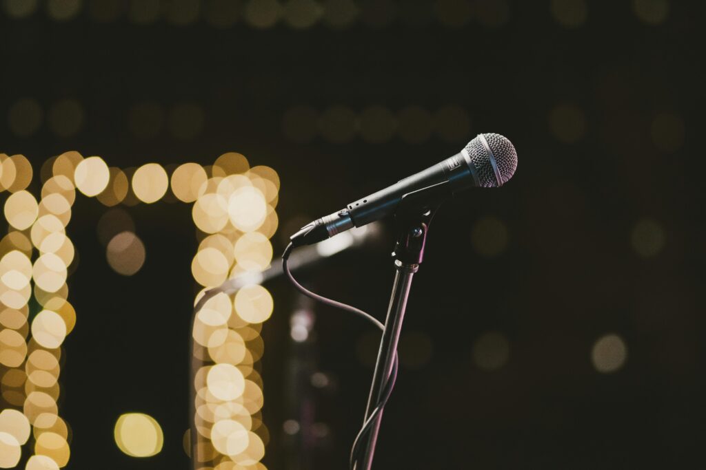 Microphone on stand with bokeh lights in the background, perfect for music themes.